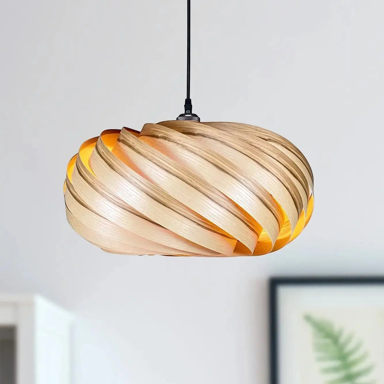 Gofurnit Quiescenta pendant lamp shade made of olive ash wood with a unique swirling design and warm interior glow.
