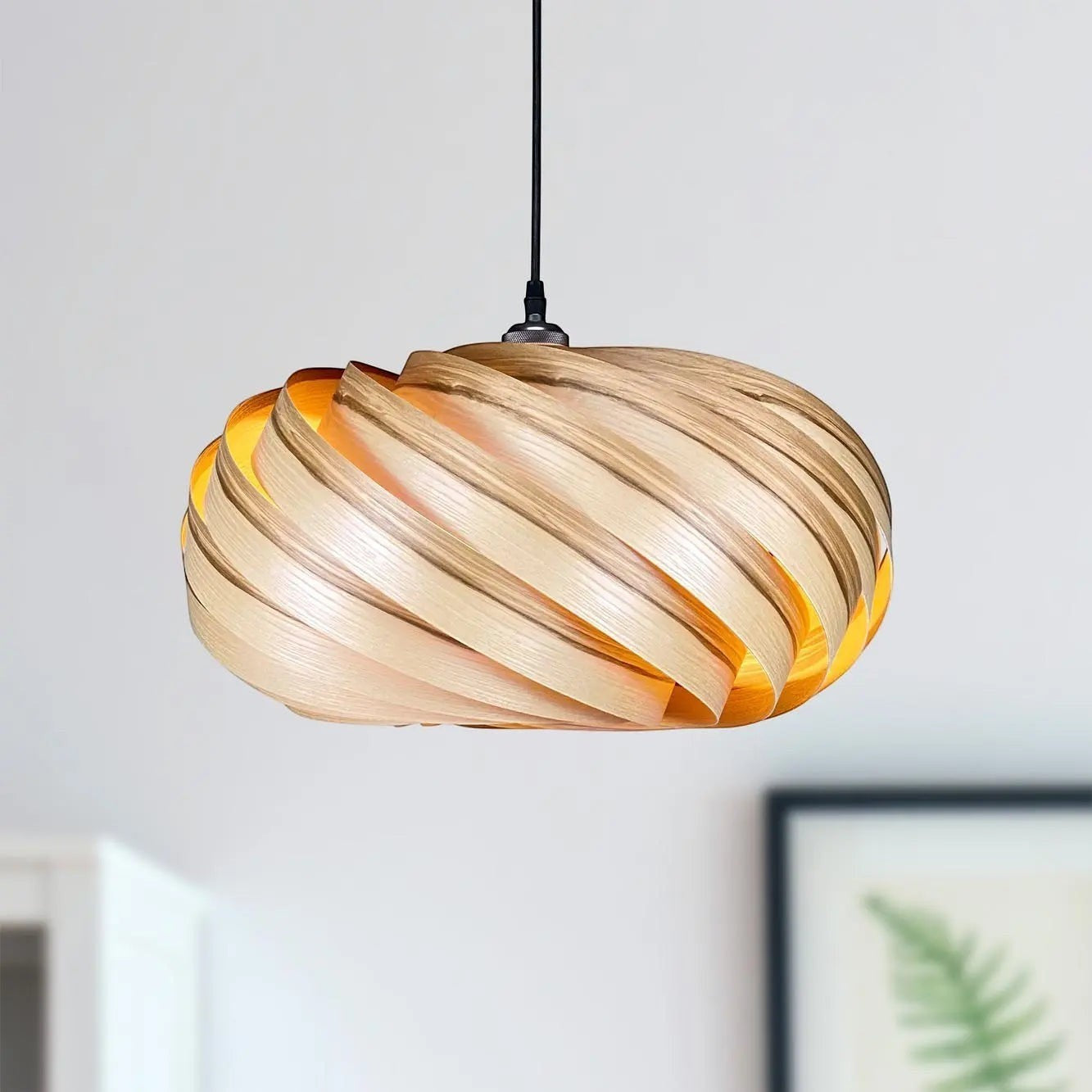 Gofurnit Quiescenta pendant lamp shade made of olive ash wood with a unique swirling design and warm interior glow.